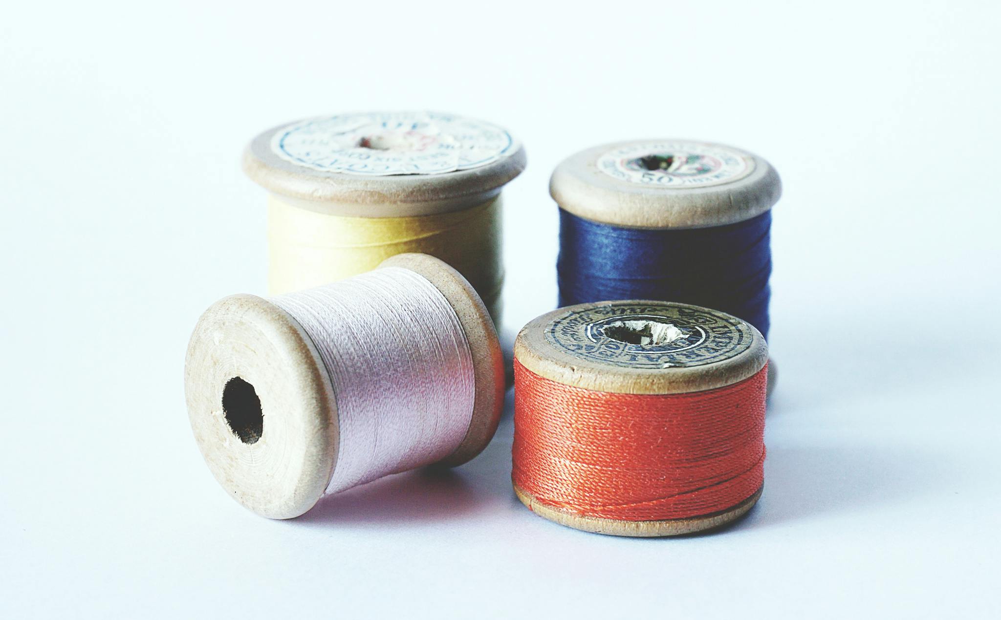 A close-up of colorful sewing threads on vintage wooden spools, perfect for arts and crafts projects.